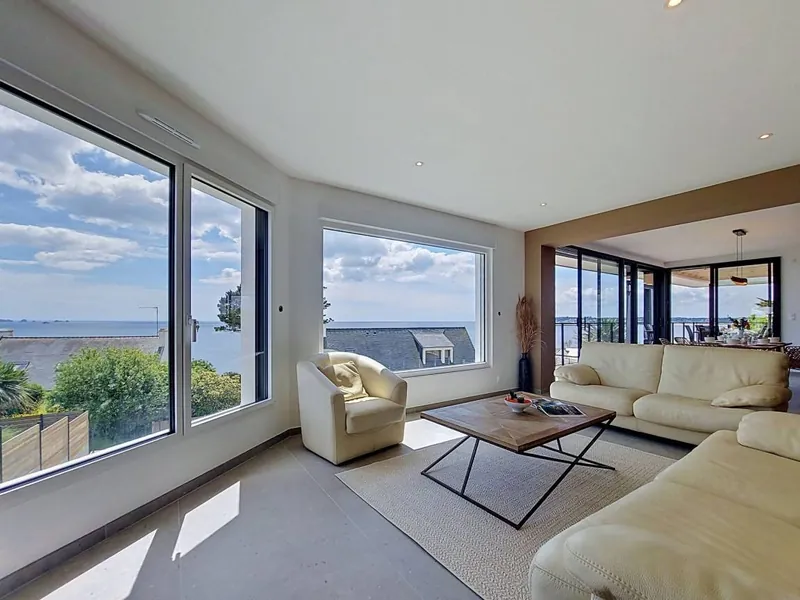 Salon lumineux avec canapés et baie vitrée sur la mer